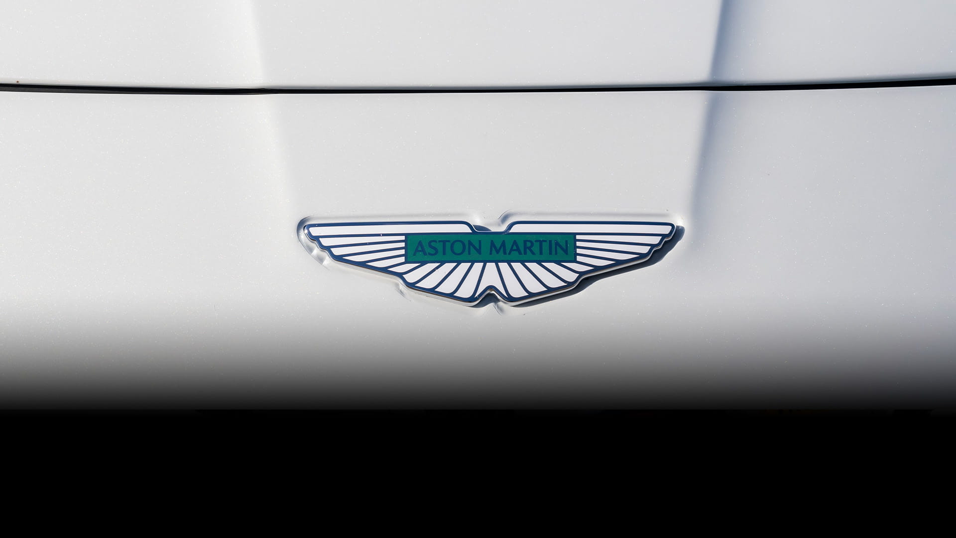 Aston Martin wings badge shown in close up on the hood of a Neutron White Vanquish