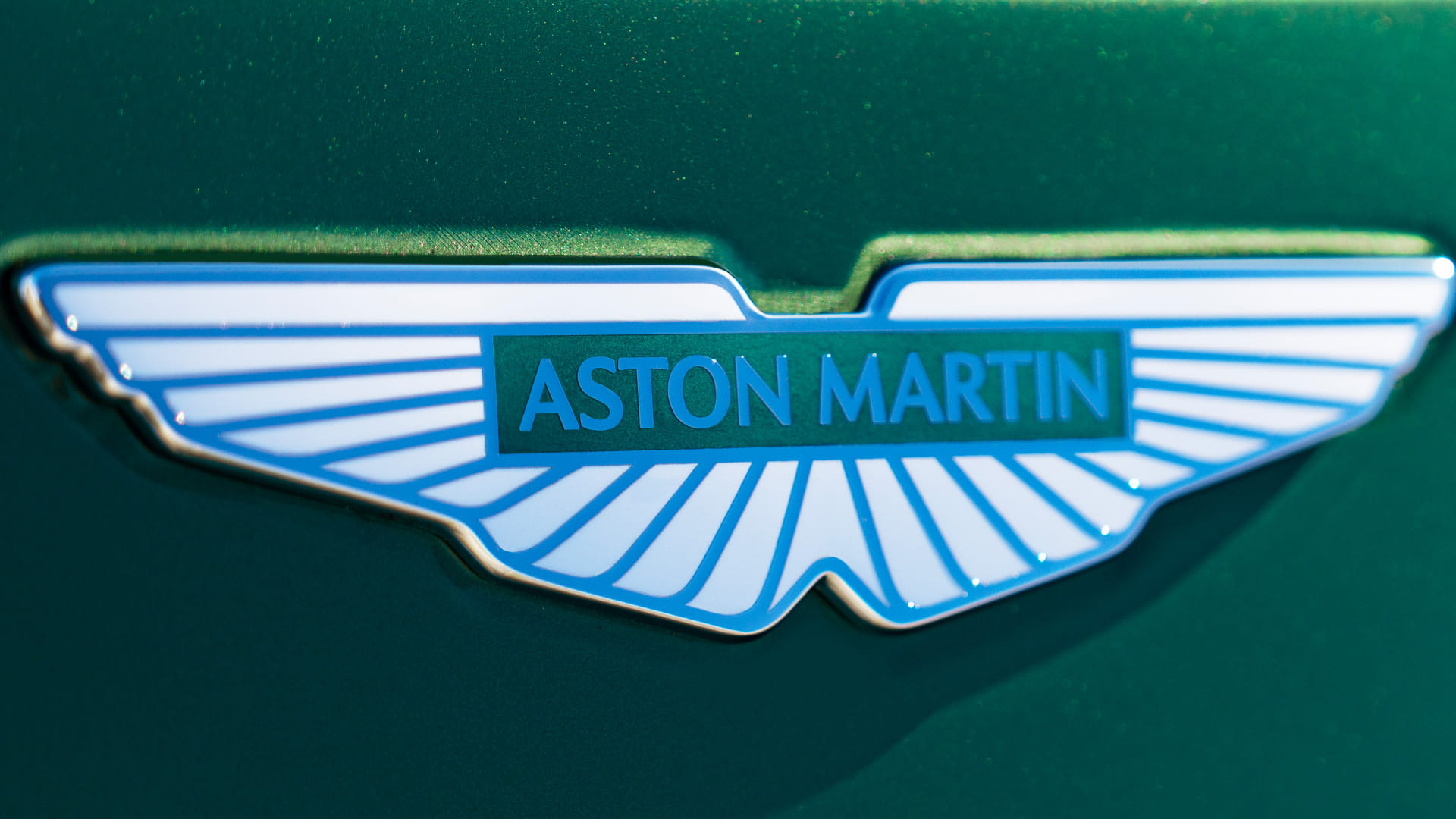 Aston Martin wings badge shown in close up on the hood of a green DB12
