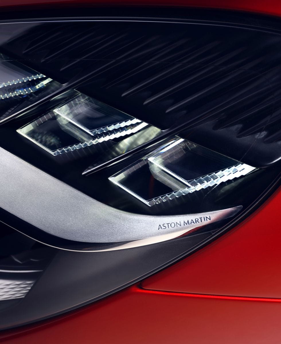 extreme close-up image shows the 'Aston Martin' name etched into a metal element of the Vanquish headlight